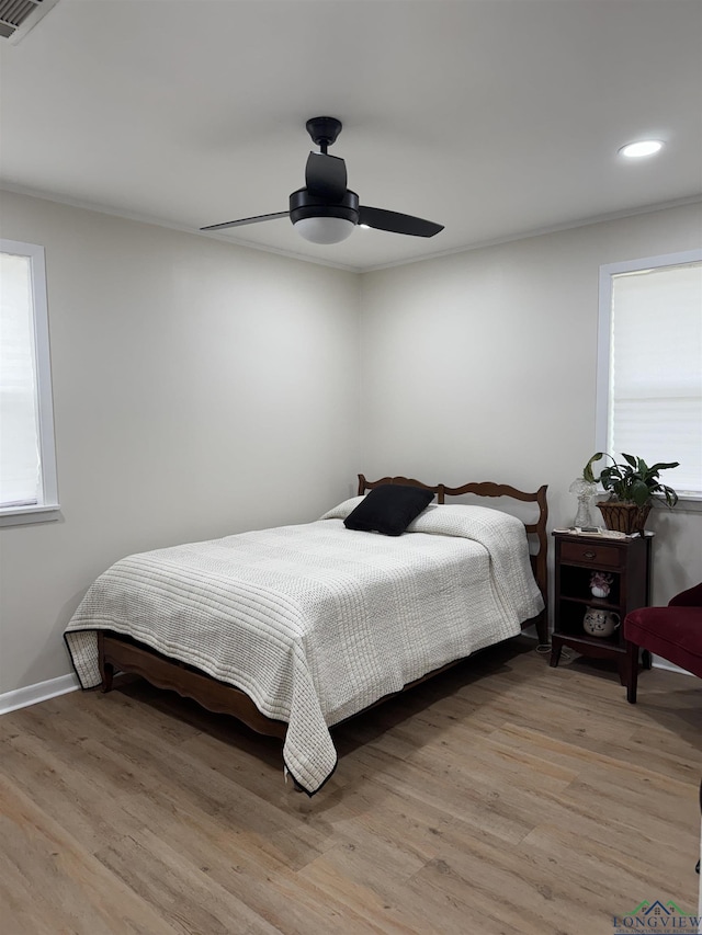 bedroom with multiple windows, light wood-type flooring, and ceiling fan