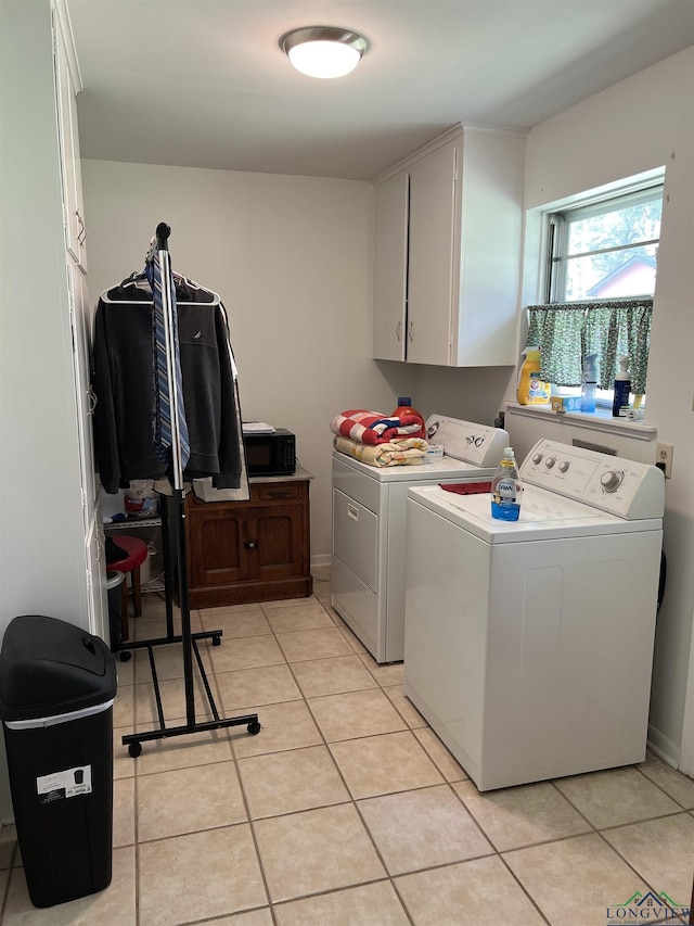 washroom with washer and dryer, light tile patterned floors, and cabinet space