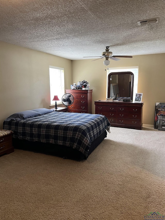carpeted bedroom with a ceiling fan, a textured ceiling, and visible vents