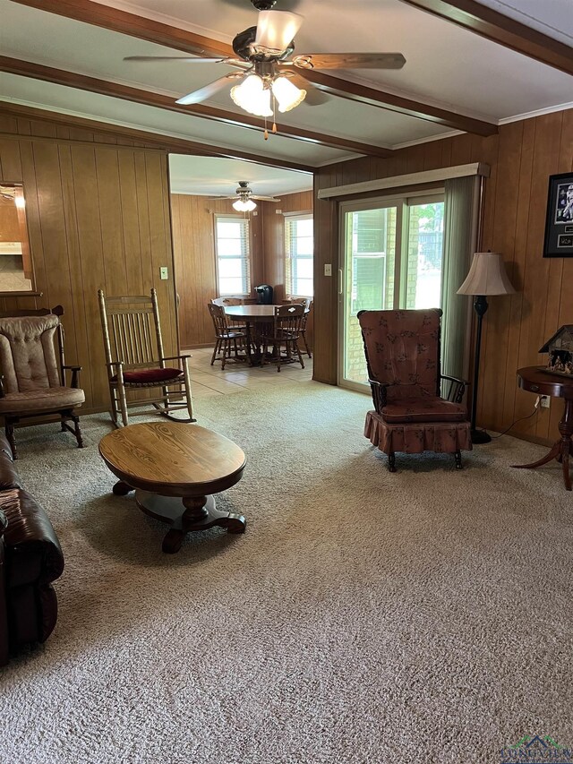 carpeted living area featuring ornamental molding, ceiling fan, beamed ceiling, and wood walls