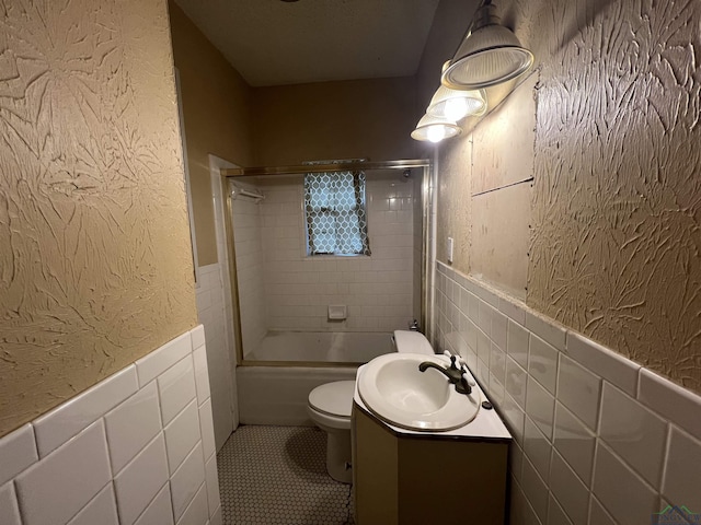 full bathroom featuring vanity, tiled shower / bath combo, tile walls, tile patterned flooring, and toilet