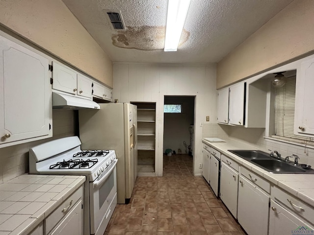 kitchen with tile countertops, white cabinetry, sink, and white gas range oven