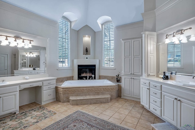 bathroom with tiled bath, tile patterned floors, vanity, and lofted ceiling