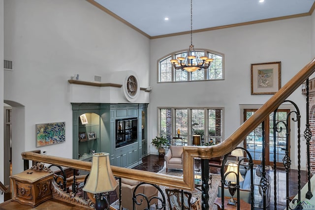 interior space with a notable chandelier, a towering ceiling, and crown molding