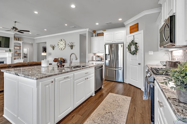 kitchen with stainless steel appliances, a fireplace, a sink, white cabinets, and dark wood-style floors