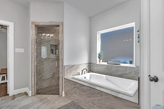 bathroom featuring a stall shower, a garden tub, and baseboards