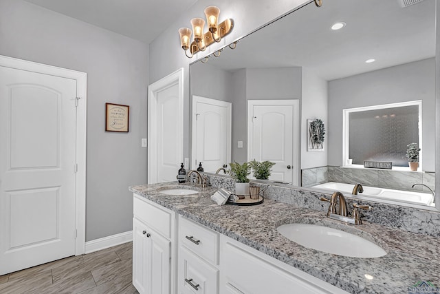 full bathroom featuring double vanity, a tub to relax in, a sink, and visible vents