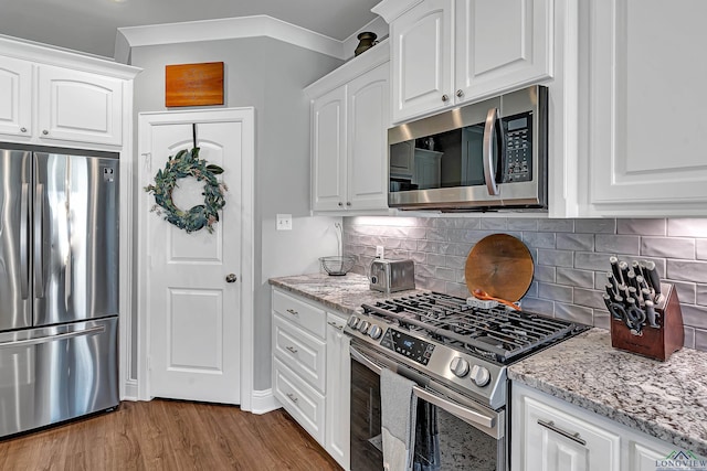 kitchen with appliances with stainless steel finishes, light stone countertops, white cabinetry, and wood finished floors