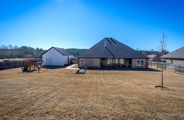 rear view of property with a fenced backyard, an outdoor structure, a lawn, and brick siding