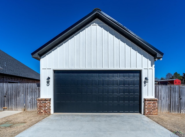 garage with concrete driveway and fence