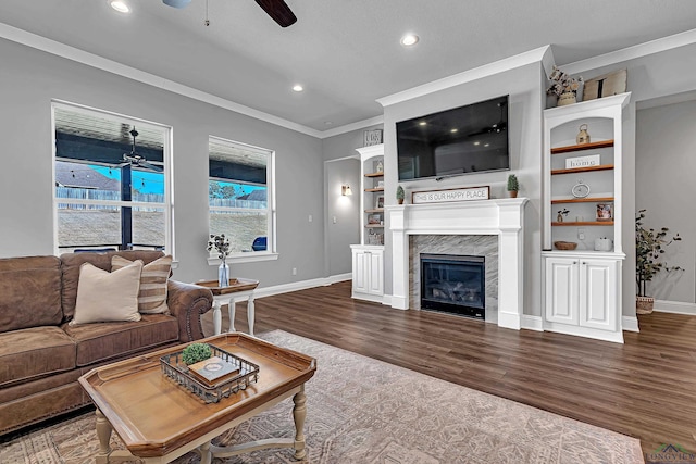 living room featuring a fireplace, wood finished floors, a ceiling fan, and crown molding