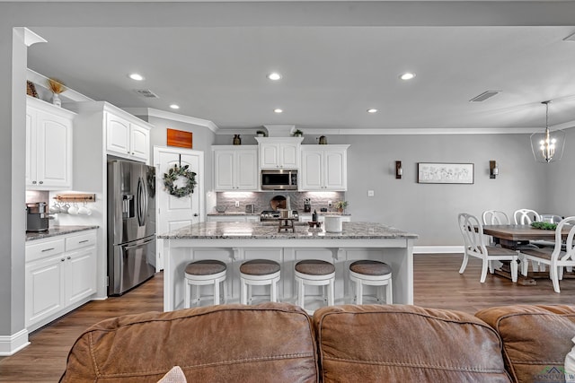 kitchen featuring stone countertops, stainless steel appliances, dark wood-type flooring, visible vents, and a kitchen bar