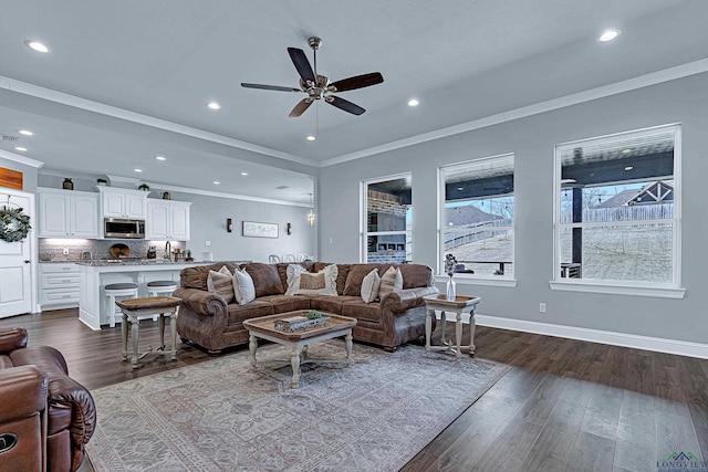 living area with baseboards, ceiling fan, ornamental molding, dark wood-type flooring, and recessed lighting