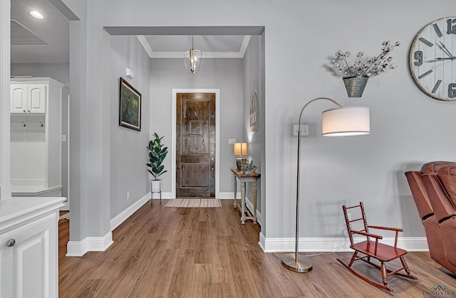 foyer entrance featuring ornamental molding, light wood-type flooring, and baseboards