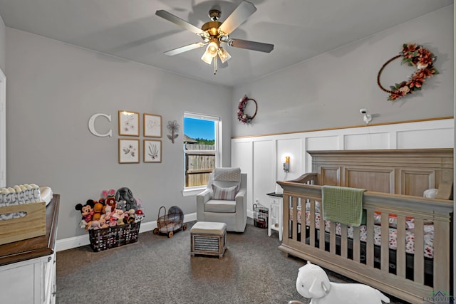 bedroom featuring a nursery area, baseboards, ceiling fan, and carpet