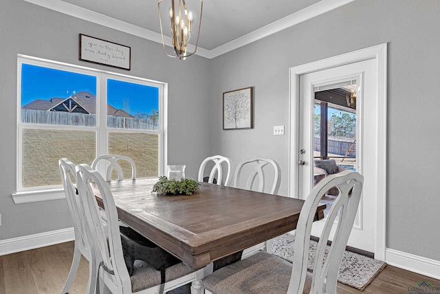 dining area with an inviting chandelier, crown molding, baseboards, and wood finished floors