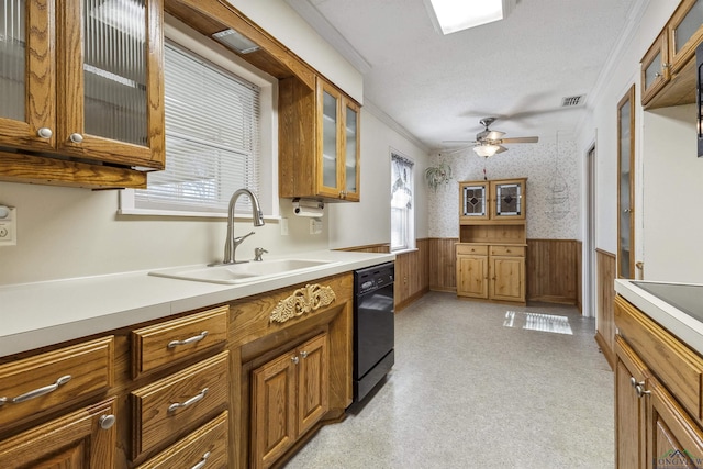 kitchen featuring ceiling fan, dishwasher, sink, crown molding, and wooden walls