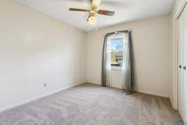 spare room featuring a textured ceiling, light colored carpet, and ceiling fan