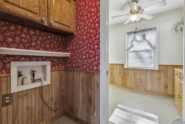 laundry area featuring crown molding, ceiling fan, and cabinets