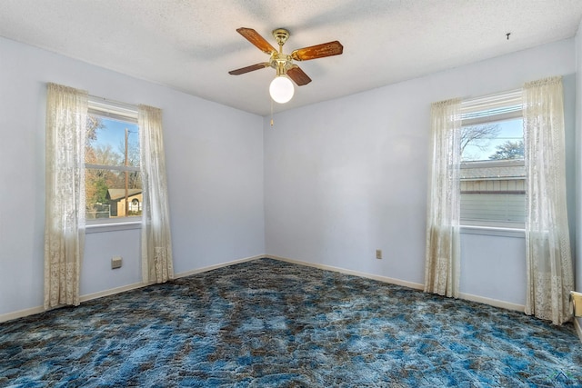 unfurnished room featuring dark colored carpet, a textured ceiling, and ceiling fan