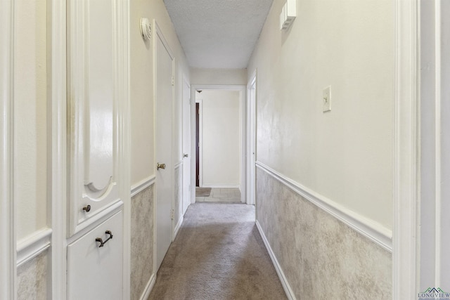 hallway featuring light colored carpet and a textured ceiling