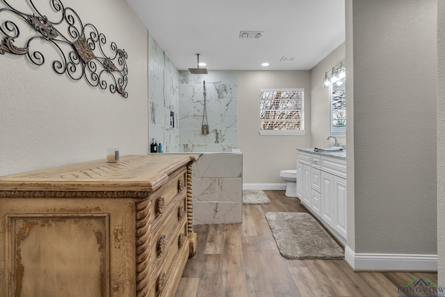 bathroom with toilet, wood finished floors, vanity, visible vents, and baseboards