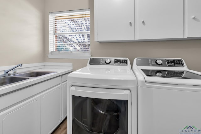 clothes washing area with cabinet space, a sink, and washing machine and clothes dryer