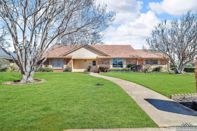 ranch-style house with a shingled roof, a front yard, and brick siding