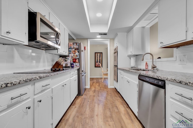 kitchen with light wood-style flooring, stainless steel appliances, a sink, visible vents, and white cabinetry