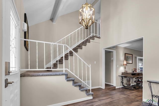 entrance foyer with a high ceiling, an inviting chandelier, wood finished floors, beamed ceiling, and baseboards