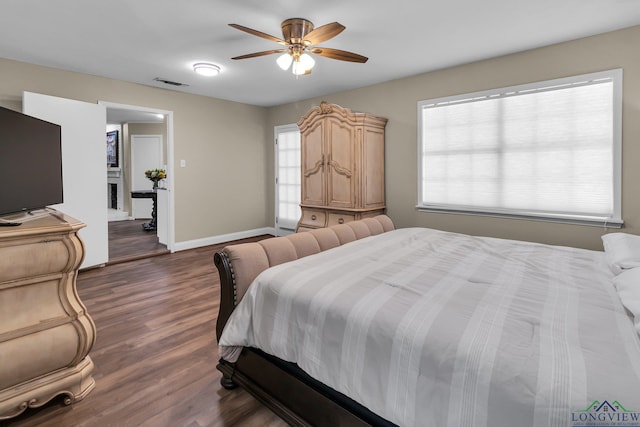 bedroom featuring baseboards, visible vents, a ceiling fan, dark wood-style flooring, and a fireplace