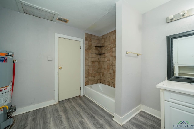 bathroom featuring water heater, hardwood / wood-style floors, vanity, and tiled shower / bath combo