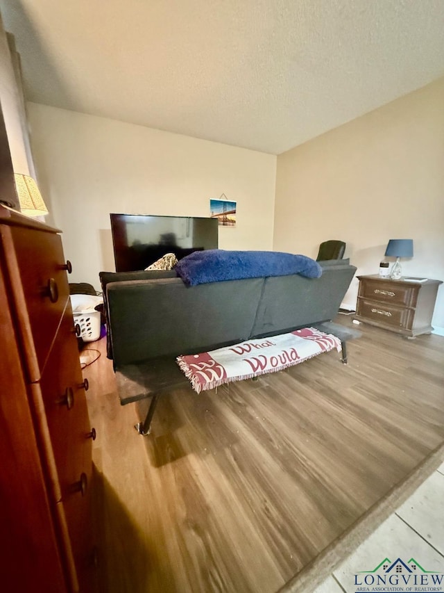 bedroom with light hardwood / wood-style floors and a textured ceiling