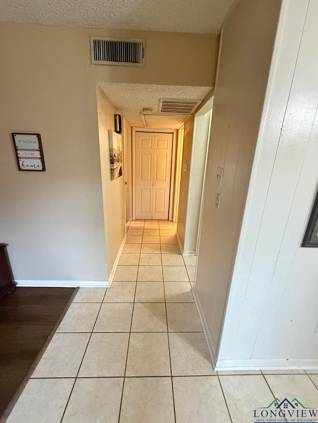 hallway with light tile patterned floors and a textured ceiling