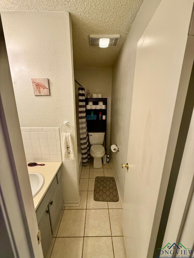 bathroom featuring vanity, toilet, tile patterned flooring, and a textured ceiling