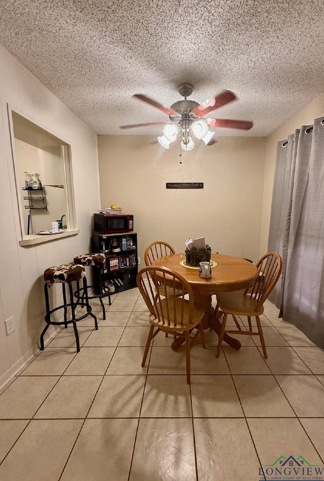 dining space with ceiling fan, light tile patterned floors, and a textured ceiling