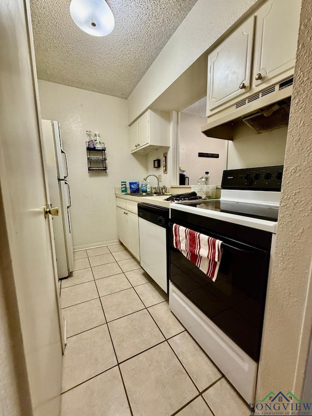 kitchen with light tile patterned floors, white appliances, sink, white cabinetry, and a textured ceiling