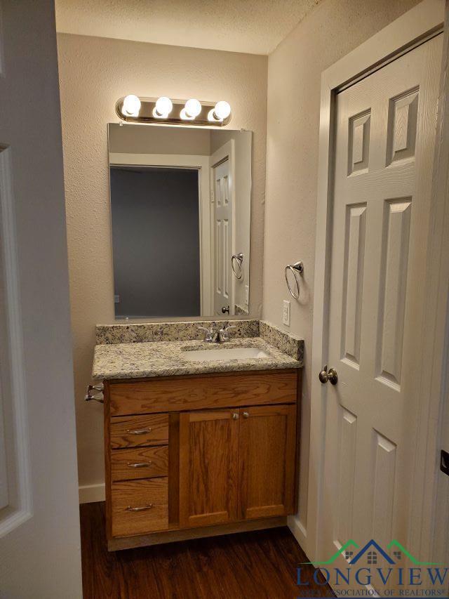 bathroom with hardwood / wood-style floors, vanity, and a textured ceiling