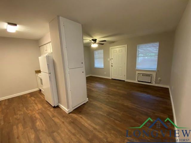 kitchen featuring ceiling fan, dark wood-type flooring, white refrigerator, an AC wall unit, and white cabinets