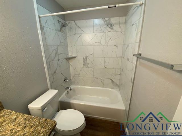 bathroom with tiled shower / bath combo and toilet