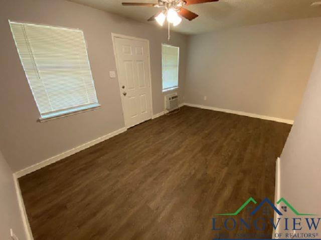 empty room featuring ceiling fan, dark wood-type flooring, and a wall unit AC