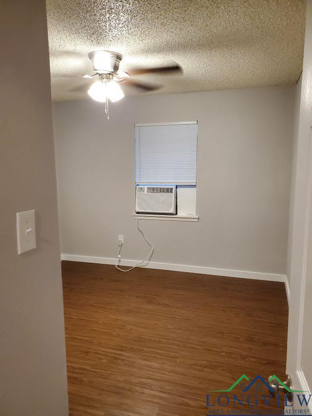 unfurnished room with dark hardwood / wood-style floors, cooling unit, a textured ceiling, and ceiling fan