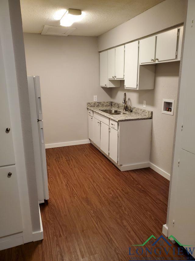 kitchen with white cabinetry, sink, dark wood-type flooring, white refrigerator, and a textured ceiling