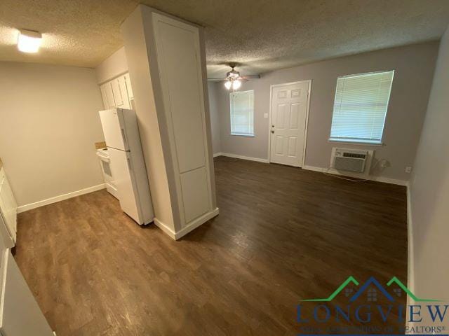 interior space with ceiling fan, a wall mounted air conditioner, dark hardwood / wood-style floors, and a textured ceiling