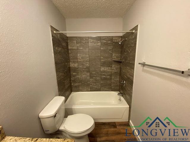 bathroom featuring tiled shower / bath, wood-type flooring, a textured ceiling, and toilet