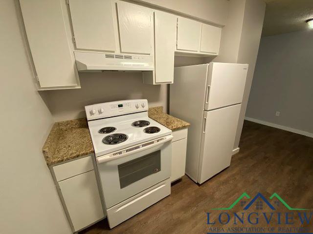 kitchen with white cabinetry, dark hardwood / wood-style flooring, white appliances, and stone counters