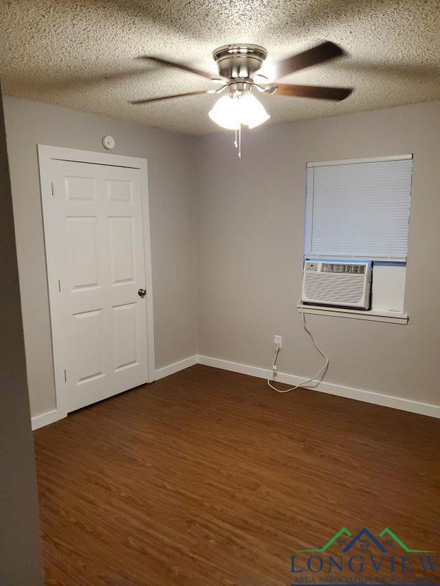 empty room featuring a textured ceiling, ceiling fan, and dark hardwood / wood-style floors