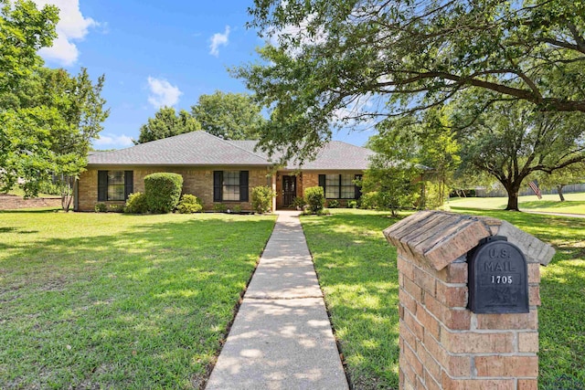 single story home with a shingled roof, brick siding, and a front yard