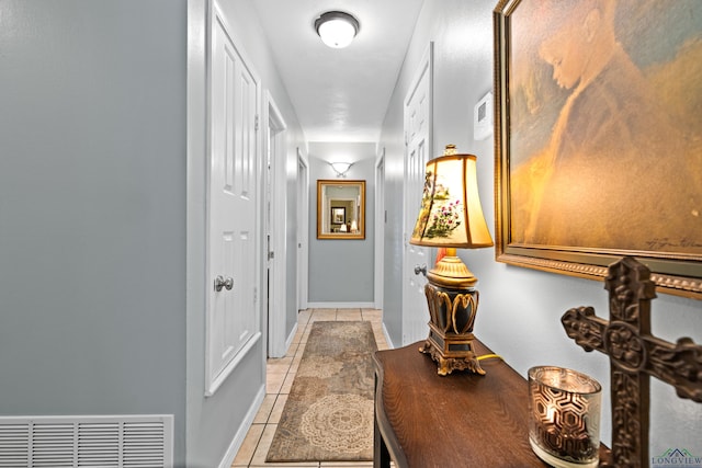 corridor with baseboards, visible vents, and light tile patterned flooring