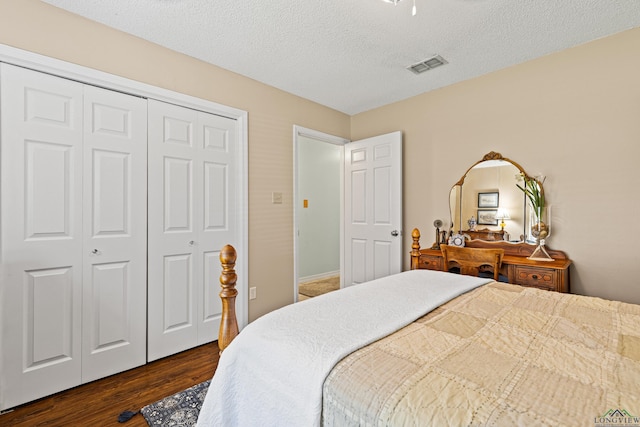 bedroom with a closet, dark wood finished floors, visible vents, and a textured ceiling
